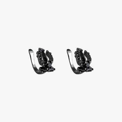 A pair of Shadow Trident black clip-on ear cuffs with black cubic zirconia stones, displayed on a white background to show detail.
