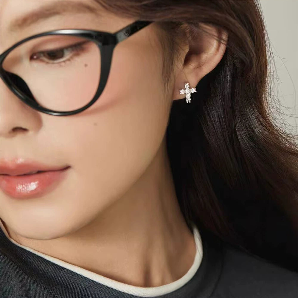 Woman in glasses wearing a silver CZ cross clip on earring on a non pierced ear