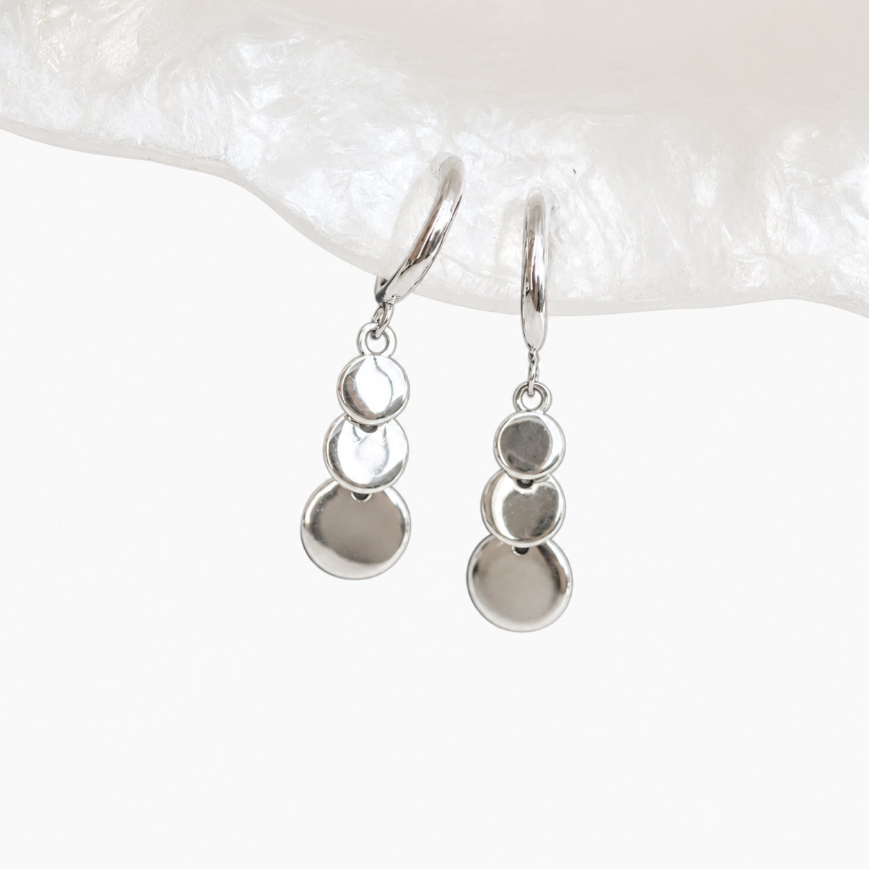 Close up detail of the graduated grey discs on silver clip on drop earrings