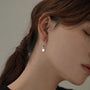 Woman wearing a silver grey disc drop clip on earring on a non pierced ear