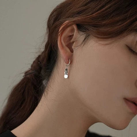 Woman wearing a silver grey disc drop clip on earring on a non pierced ear