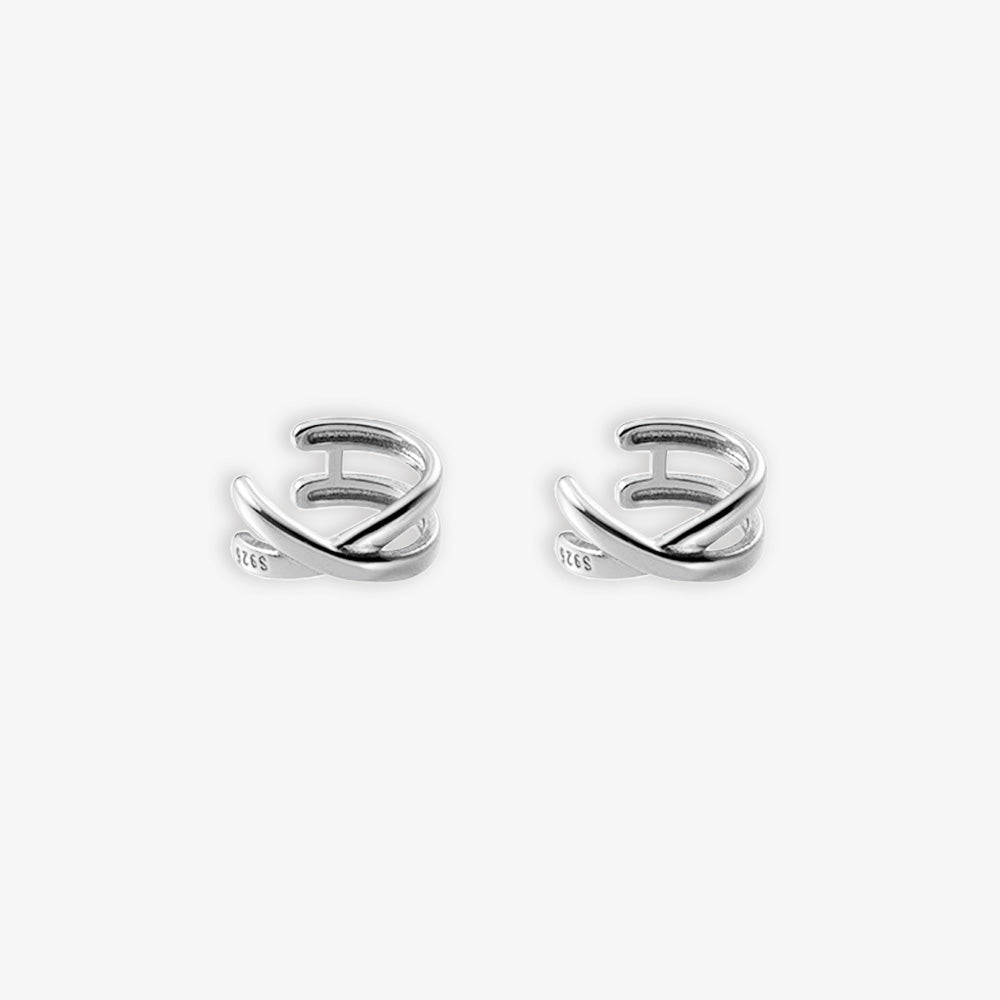 A pair of shiny silver Helix Cross Ear Cuffs against a white backdrop. These conch cuffs boast a spiral design that snugly fits the ear, making a statement perfect for special events or as a striking addition to formal wear.