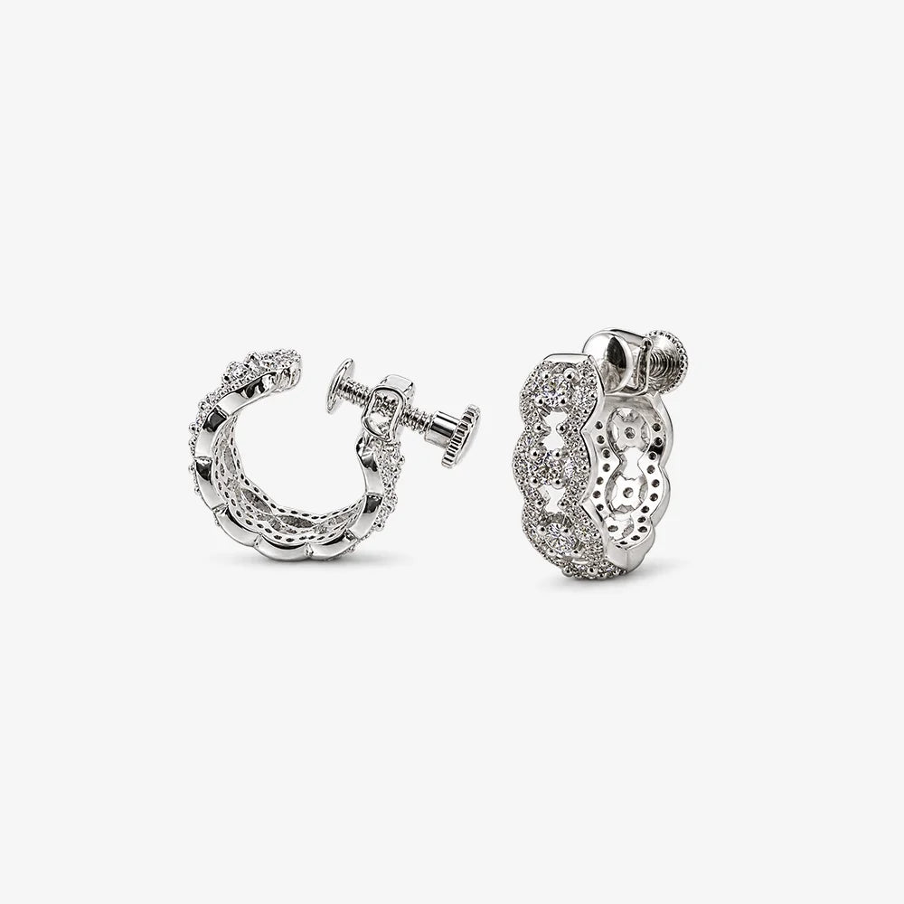 A pair of silver huggie hoop earrings adorned with clear pavé-set crystals, shown from both the front and side angles on a light gray background.