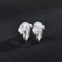 Une paire de boucles d'oreilles à clip solitaire argentées, ornées de pierres en oxyde de zirconium transparentes et munies de clips rembourrés, présentées sur un fond noir.