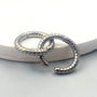 Two silver twisted rope clip-on hoop earrings interlinked, showcasing the seamless spring closure and textured detail.