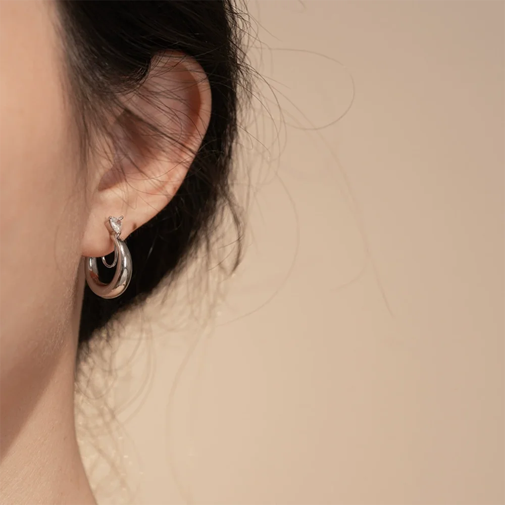 Small thick hoop clip-on earring with a heart CZ worn on a non-pierced earlobe