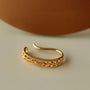 Detailed side view of the floral filigree gold ear cuff, highlighting the intricate cutout pattern and milgrain edges.