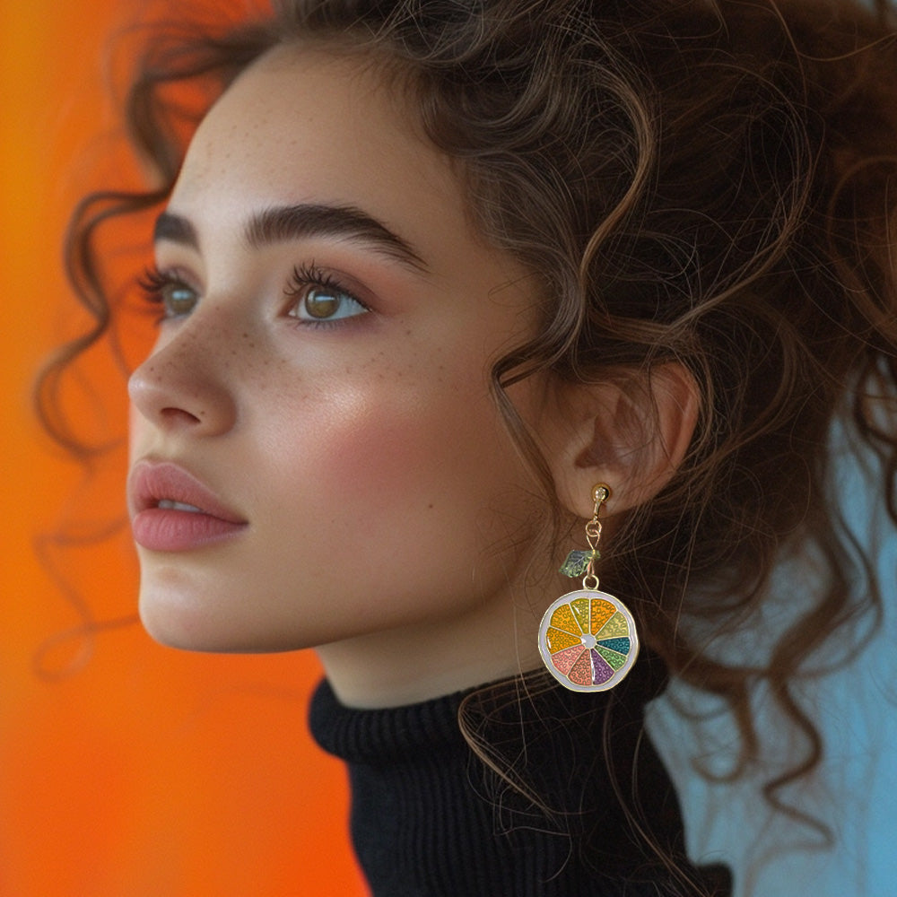 Woman wearing drop earrings featuring vibrant orange slices. Perfect for pride month events, summer looks or everyday look.