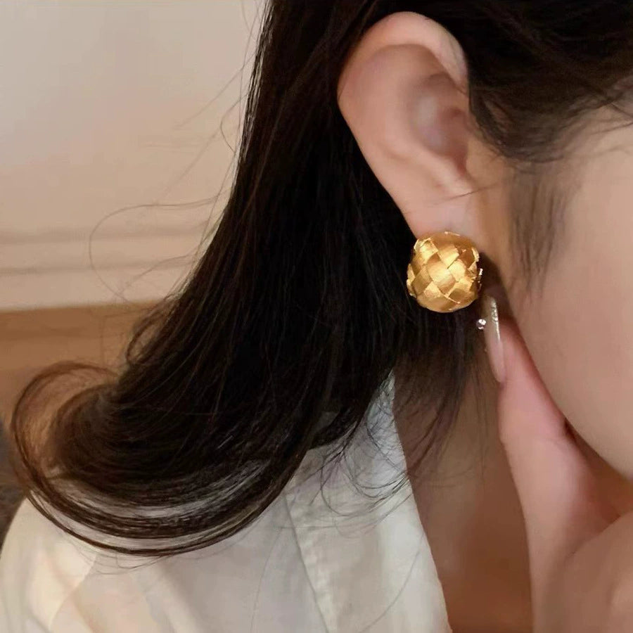 Woven gold dome hoop clip-on earring worn on a non-pierced earlobe