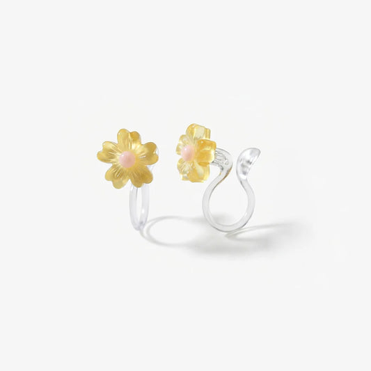 Close-up of the translucent yellow resin daisy petals and the clear stud invisible clip-on mechanism for non-pierced ears.